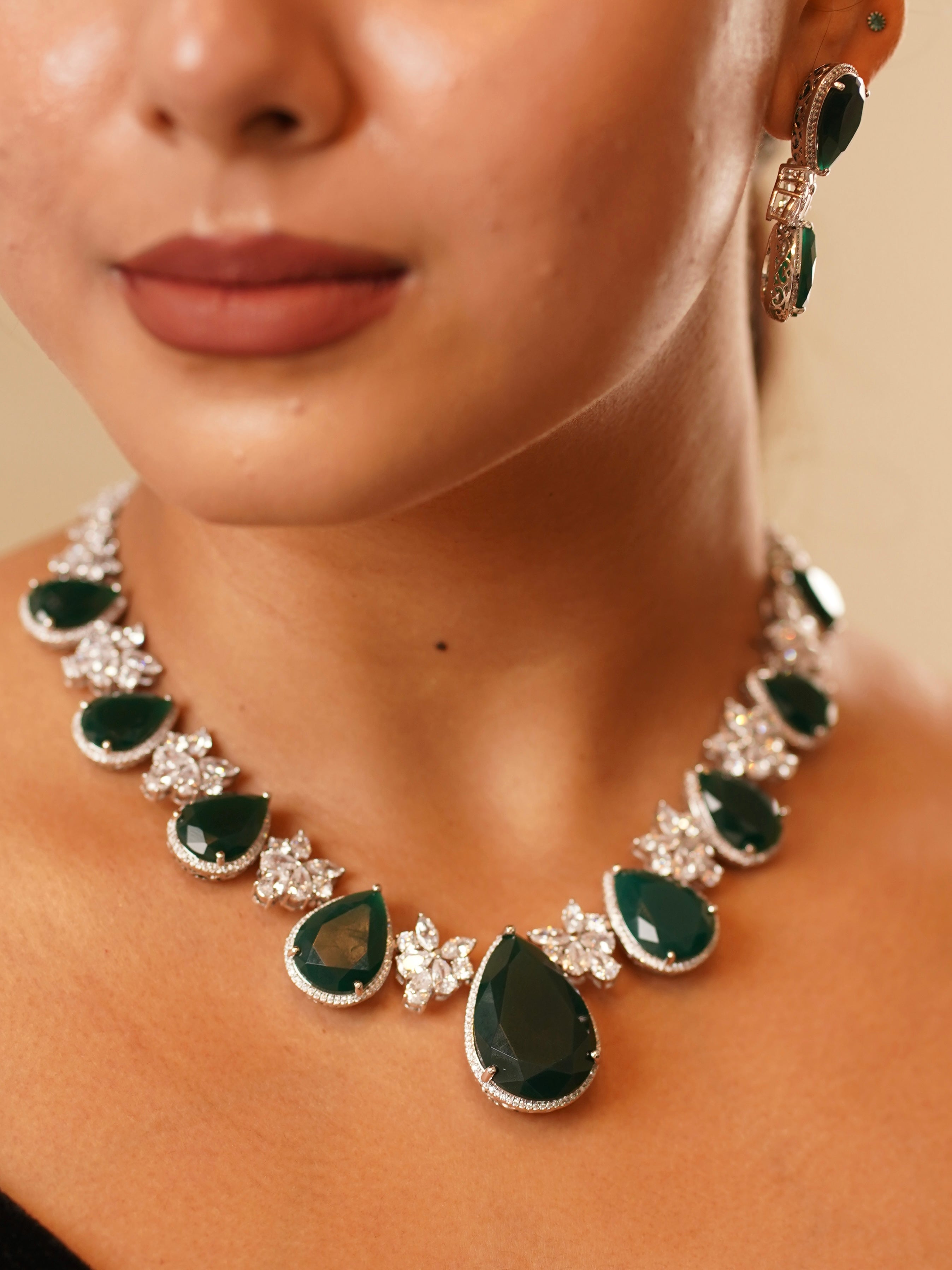 emerald teardrop necklace with zircon accents and matching drop earrings laid flat